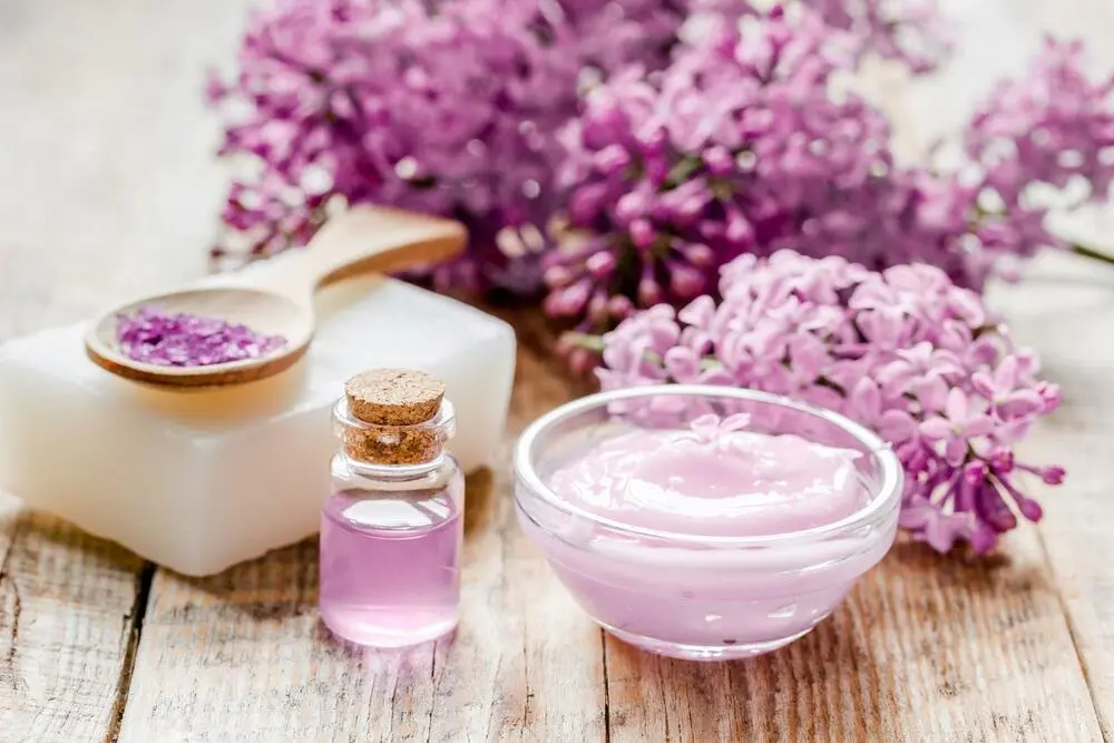 Bio-Salz, Sahne, Extrakt in lila Kosmetikset mit Blumen auf Holztischhintergrund
